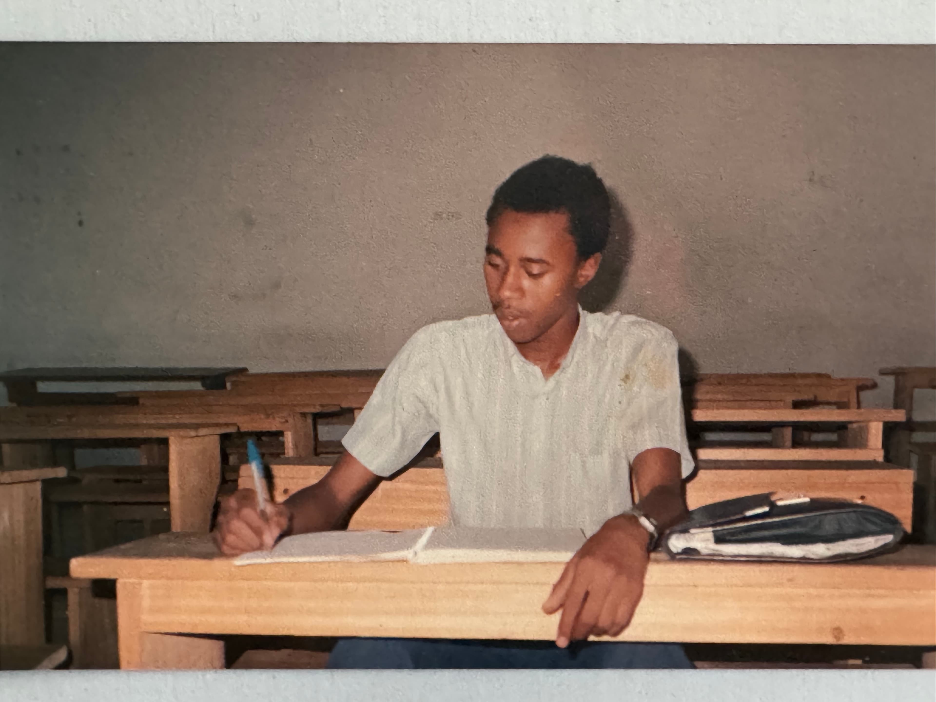 A young Mahamouda Salouhou writing at a school desk
